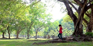 一个年轻女孩在公园的树下散步