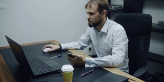 侵略性的商人看着电话和电脑，侵略性地抛出一杯咖啡，愤怒的人，工作中的被动攻击性概念，慢动作