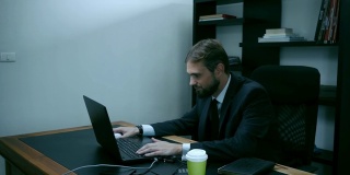 大胡子商人坐在办公室的笔记本电脑前，红衣女郎正试图勾引老板，慢镜头