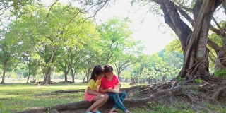 在一个阳光明媚的夏日，女孩们坐在树下看书