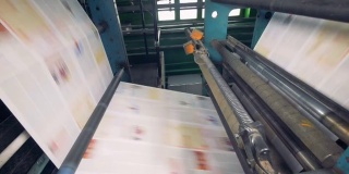 印刷设备在工作，特写。在工厂里，纸张快速地通过传送带传送。