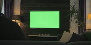 绿屏人在客厅看电视。过肩射击。