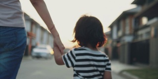 小男孩牵着妈妈的手走在街上。