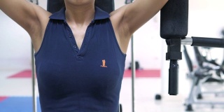 年轻的健身女士在体育馆里用力量锻炼机锻炼肌肉