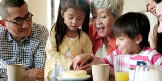 孩子们在家人的陪伴下在家切生日蛋糕