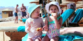 两个小女孩在海滩上吃牛角面包。沙姆沙伊赫。埃及。