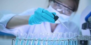 一名亚洲科学家在实验室的试管中滴下固体。医疗保健的概念。
