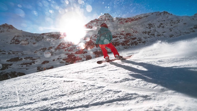SLO MO TS女滑雪板在一个斜坡上，太阳在山的后面照耀