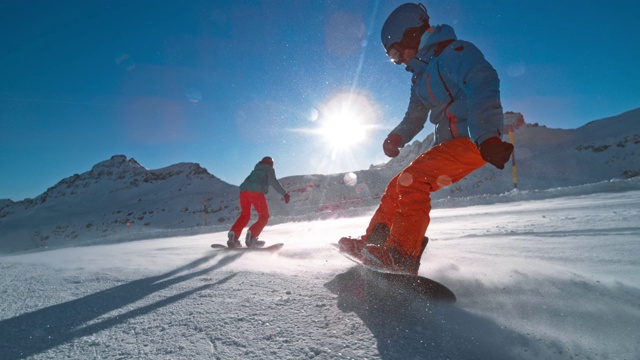 SLO MO TS两名滑雪板运动员在阳光下下山