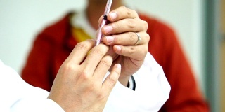 医生用注射器从药瓶中吸药治疗病人