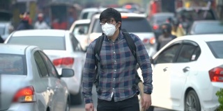 一名亚洲男子戴着口罩在交通中行走