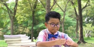 亚洲男孩在户外使用智能手机和看书。家庭观念、教育观念、小学观念、成长观念、学习观念、发展观念。4 k决议。
