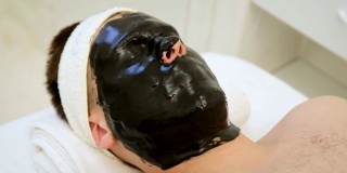 在水疗中心护理男士皮肤。美容师为男士做面部清洁、美容面膜和皮肤护理。
