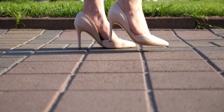 女人们穿着高跟鞋走在城市的街道上。穿着高跟鞋进城的年轻女子的脚。女孩走在人行道上。低角度视角慢动作特写
