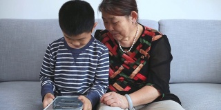 孙子和奶奶在用平板电脑玩围棋