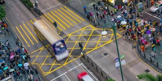 在中国香港尖沙咀区，人们和出租车穿过一个非常繁忙的十字路口