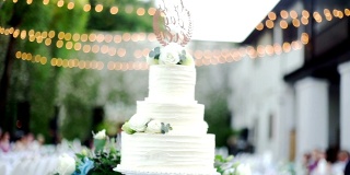 在模糊的背景下拍摄户外派对上的婚礼蛋糕和装饰灯泡。