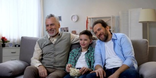 快乐的爷爷，爸爸和儿子在看电视上的喜剧节目，一起玩得很开心
