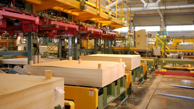 一辆铲车在生产胶合板、刨花板和其他木制品的木工工厂的区域内运输带有胶合板的包裹