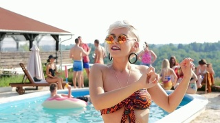 美丽的千禧金发女人在比基尼唱歌和跳舞在泳池派对视频素材模板下载