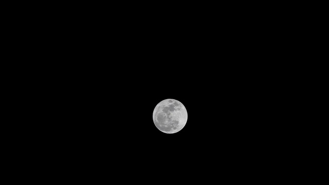 美丽的满月明亮地照耀着黑暗的夜空，照相机倾斜下来。