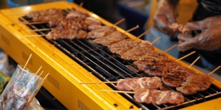 热烤架上木串上多汁的鲜肉，慢镜头。美味的烧烤是在户外油炸的