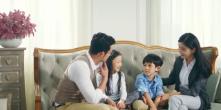 亚洲母亲和父亲在家里与儿子和女儿聊天