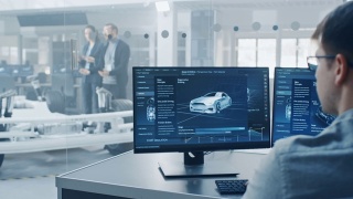 专业工程师在电脑上工作与3D软件，而同事检查电动汽车底盘原型车轮，电池和发动机站在一个高科技开发实验室。视频素材模板下载