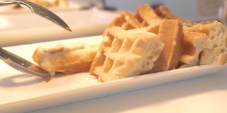 传统的比利时华夫饼躺在白色盘子上的自助餐在酒店餐厅。甜烤华夫饼作为早餐。甜点食品的概念。饮食和营养