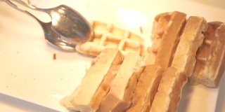 在酒店餐厅的自助餐上，手拿白盘子上的比利时华夫饼。甜烤华夫饼作为早餐。甜点食品的概念。饮食和营养