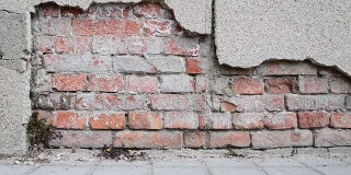 老房子或建筑物地基不良，墙面灰泥开裂，背景为砖