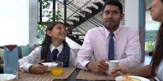 愉快的拉丁美洲家庭一起吃早餐，一边聊天一边微笑