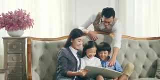 亚洲母亲和父亲读书与儿子和女儿在家里