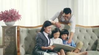 亚洲母亲和父亲读书与儿子和女儿在家里视频素材模板下载
