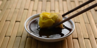 蒸猪肉饺子用木筷子夹，蘸酱油