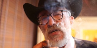 有型的老人抽着雪茄，烟从嘴里释放出来
