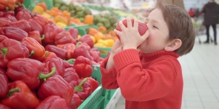 小男孩在超市里闻着保加利亚红辣椒
