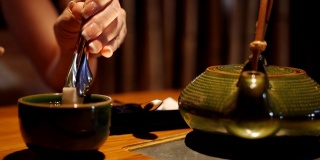 这个女人用特制的钳子把方糖放在餐厅里的一杯茶里。