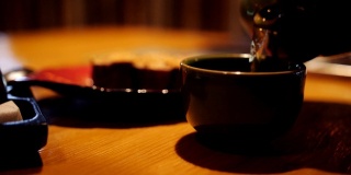 在一家泛亚洲餐厅里，一位女士在往茶杯里倒茶。