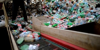 这个工人用铲子推着塑料瓶进行回收。在一家回收工厂工作