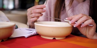 特写一盘饺子在餐厅里，一个女孩用刀叉吃着热饺子。