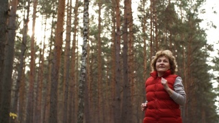 在树林里跑步的老年运动妇女视频素材模板下载