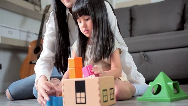 孩子们和妈妈在客厅地板上玩积木。一天在一个孩子的生活，教育理念。