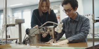 中镜头的两个中年设计专业人员一起工作在纺织制造工作室