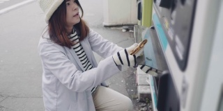亚洲女性用智能手机在自动售货机上付款。