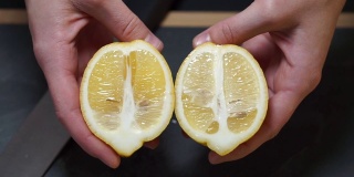 靠近点，一个女人的手拿起一把刀，把黄色的柠檬切成两半