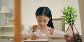 亚洲小女孩坐在书桌前写字或画画