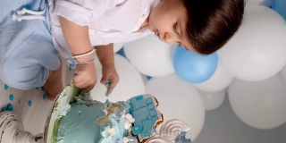 两岁的男孩和一辆车一起吃着节日的蓝色蛋糕