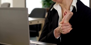 在笔记本电脑上打字的女性经理患有手腕疼痛和腕管综合症