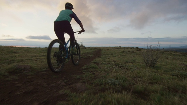 两名骑手(一名女性和一名男性)山地自行车在洛基山脉以西的丹佛，科罗拉多州日出